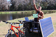 Foto de un joven sentado en una bicicleta con paneles solares